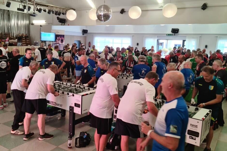 Volles Turnier mit zahlreichen Teilnehmern, die an mehreren Tischkickern in einem gro&szlig;en Saal spielen.